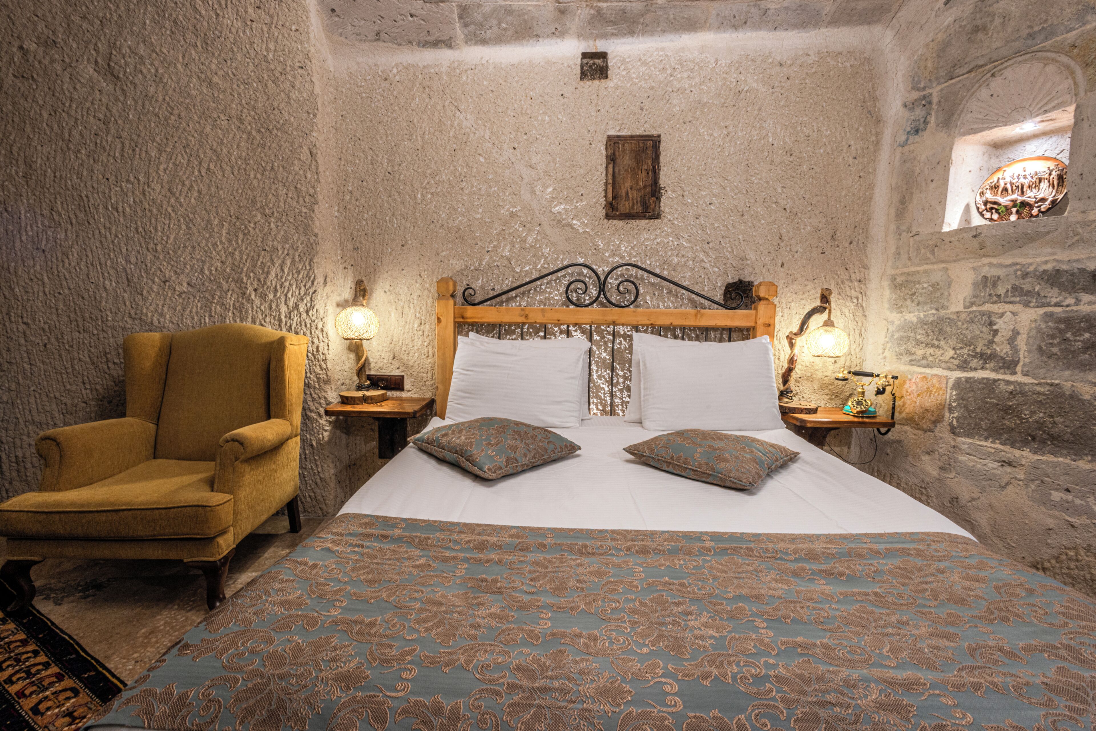A room with a large bed, a wooden chair, and two bedside tables with lamps.