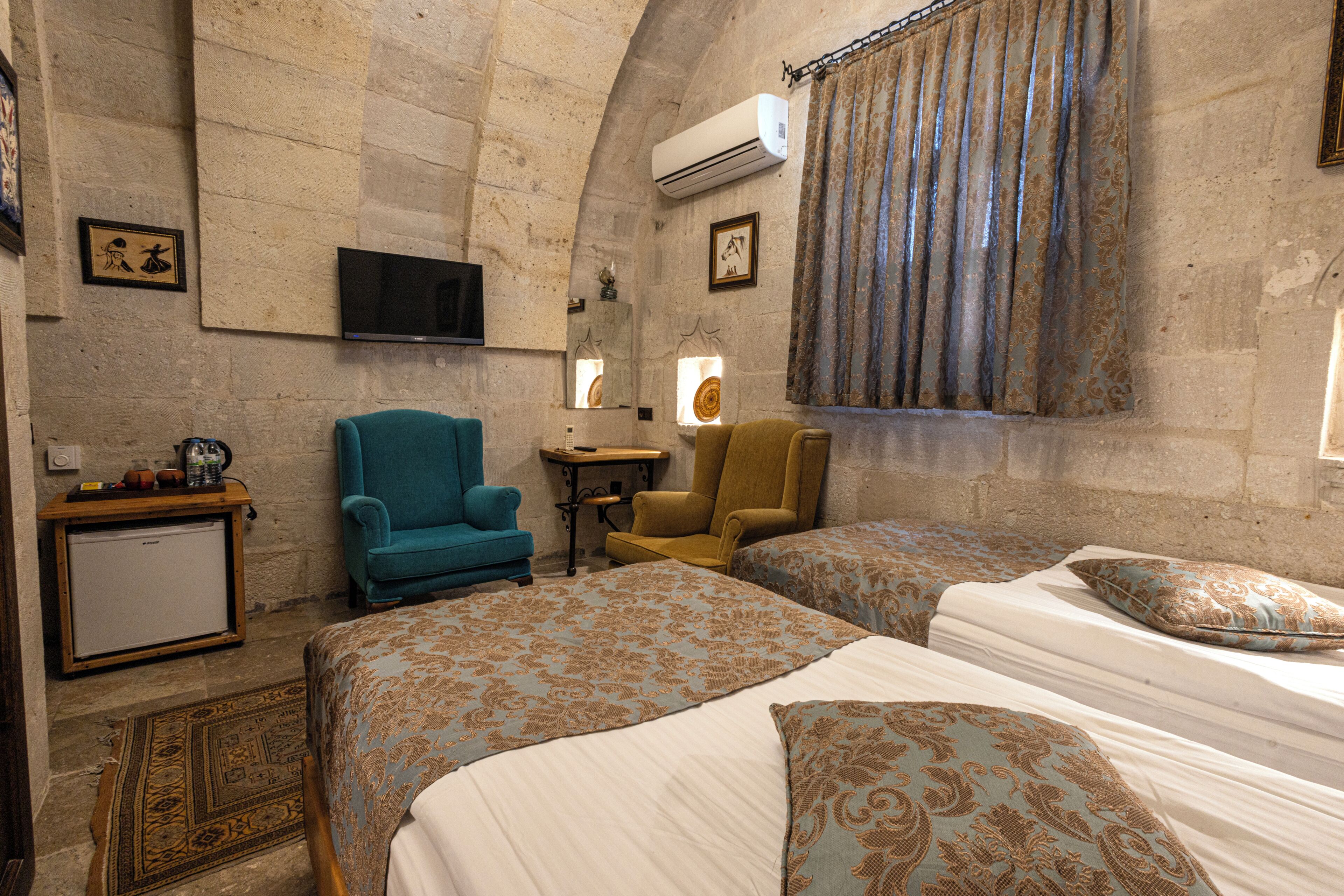 A hotel room with two beds, a television, a small table, and a chair.