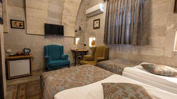 Habitación de hotel con dos camas, un televisor, una mesita y una silla.