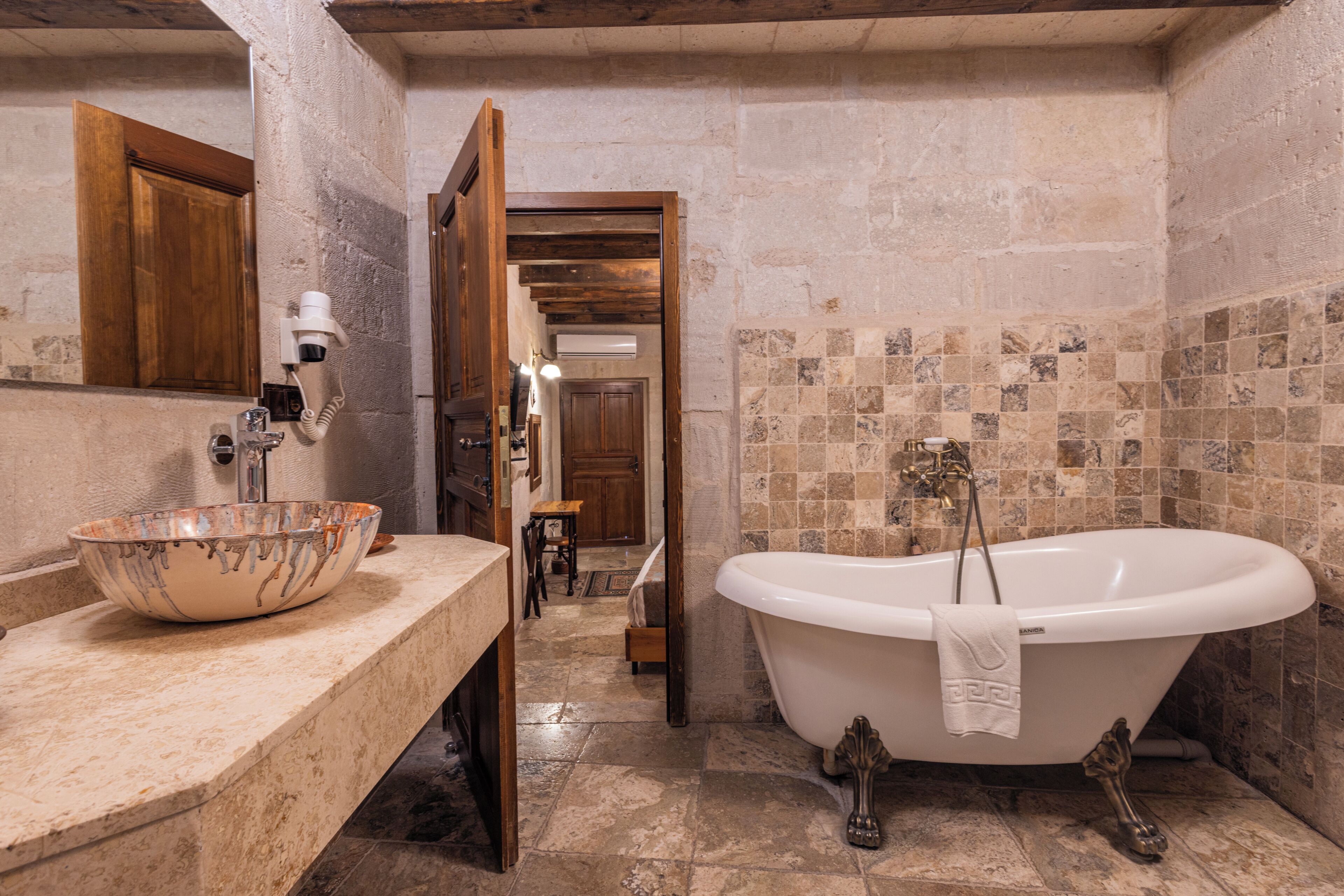 A bathroom with a freestanding bathtub, a large ceramic basin, and a wooden vanity.