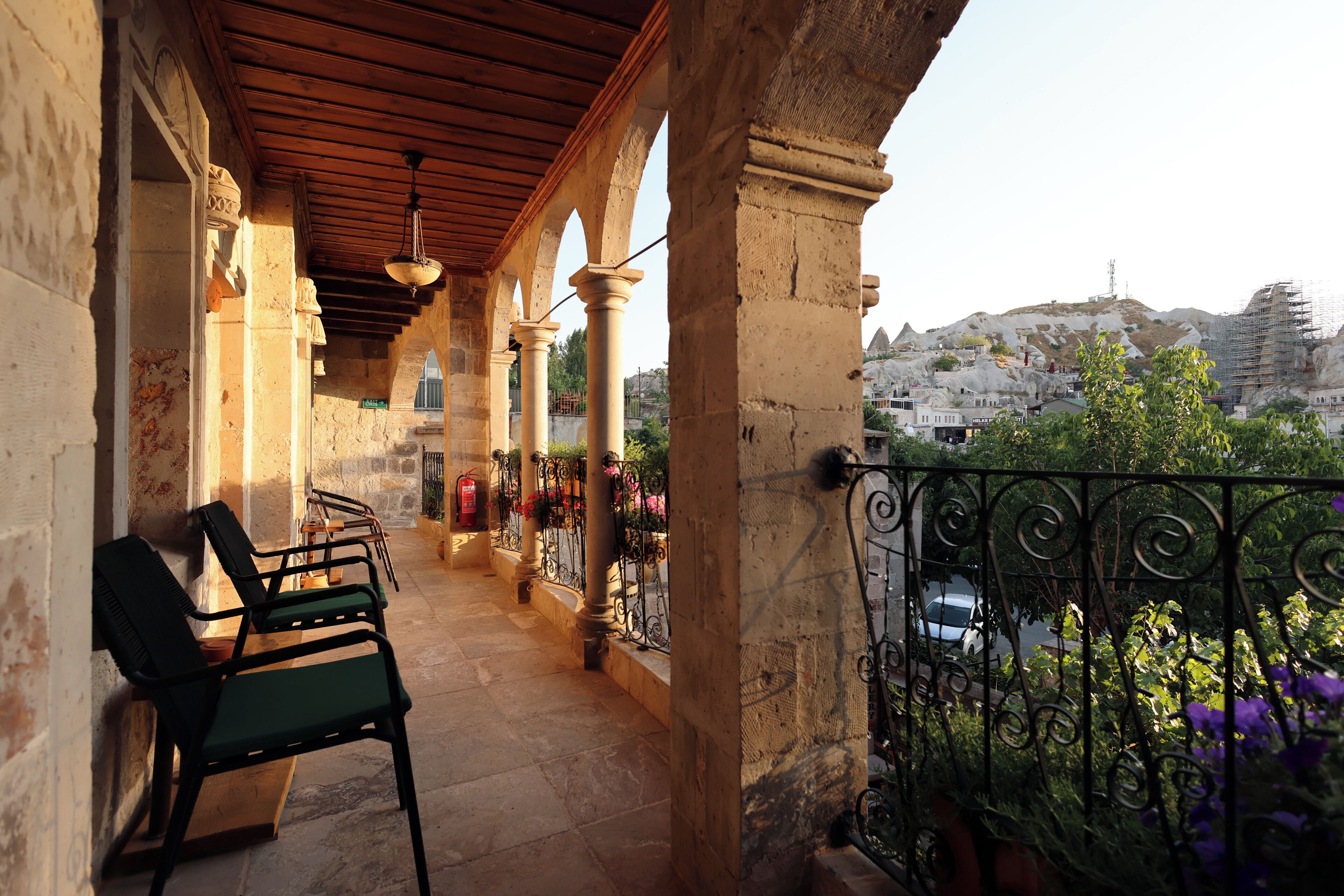 A balcony with a view of a mountainous landscape, a fire extinguisher, and a chair.