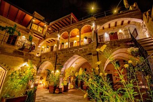 Un patio con arcos de piedra, plantas en macetas y una escalera de madera.