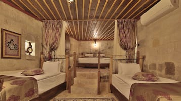 A room with two beds, a wooden staircase, a chandelier, and a wall-mounted air conditioner.