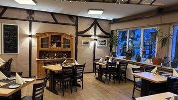 Interior acogedor de un restaurante con mobiliario de madera, un menú en pizarra y vistas por la ventana.