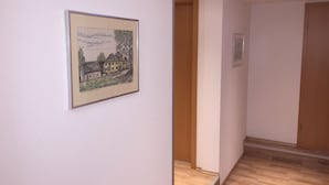 A hallway with a framed picture of a building, wooden flooring, and a wooden door. - Pension im Wirtshaus Himberg (Bad Honnef)