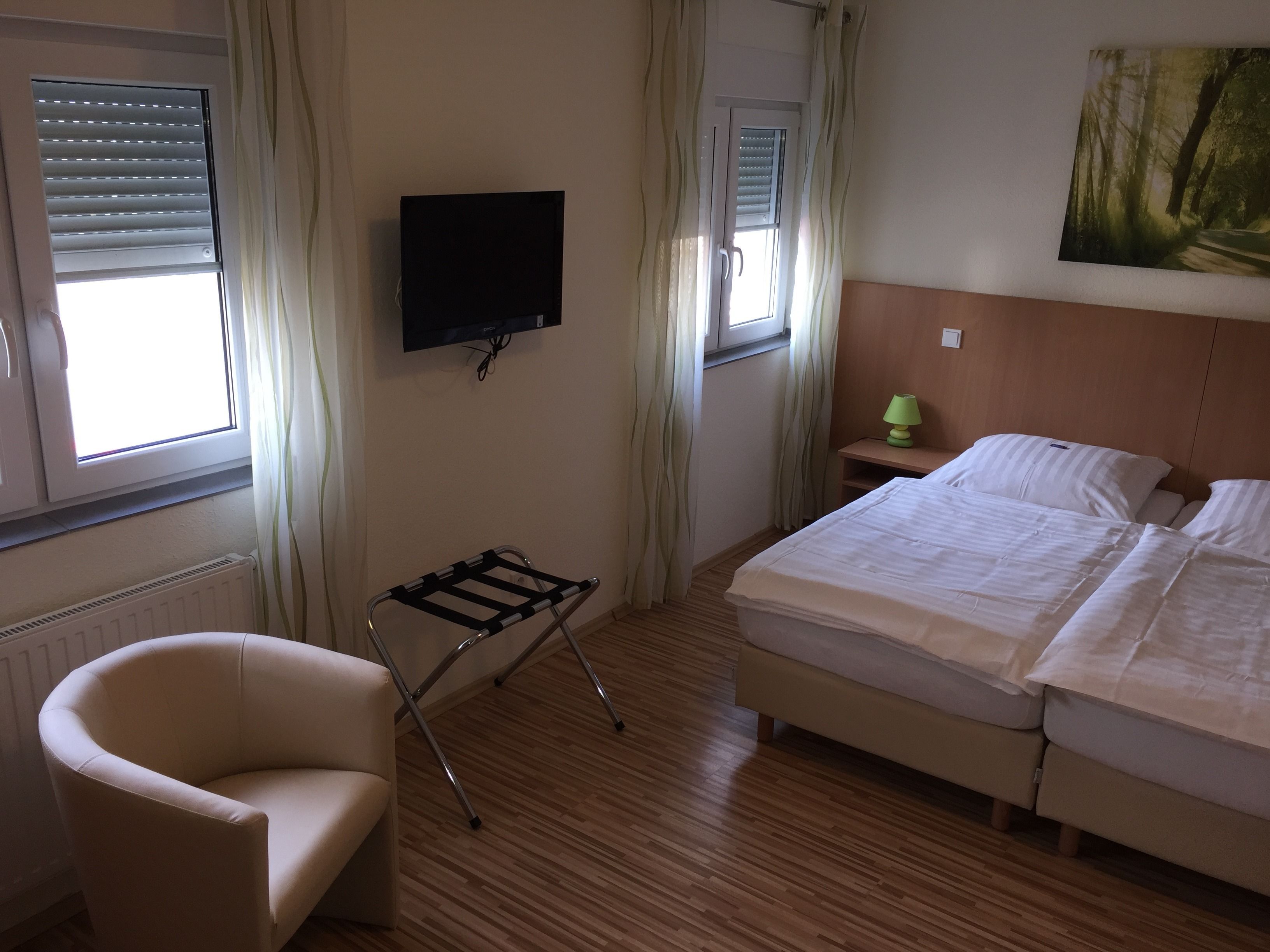 Ein Hotelzimmer mit einem Bett, einem Sessel, einem an der Wand montierten Fernseher und einem Wandbild.
