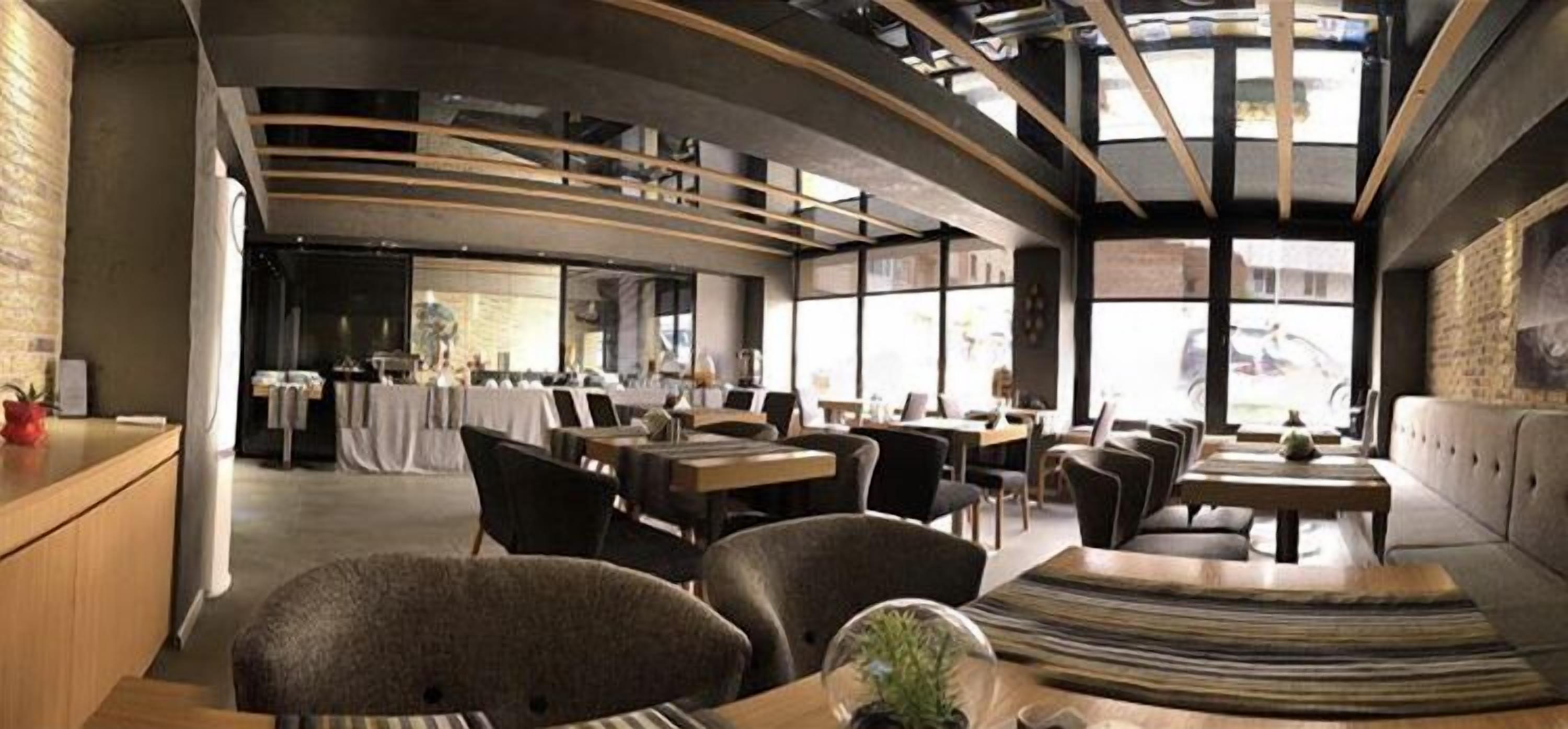 Een modern restaurant met een gebogen plafond, grote ramen en verschillende zithoeken, inclusief tafels en stoelen.