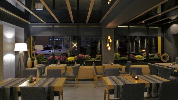 A modern restaurant with a cozy interior, featuring wooden tables and chairs, and a view of the street outside. - The Black Hotel (Eskisehir)