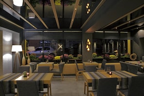 A modern restaurant with a cozy interior, featuring wooden tables and chairs, and a view of the street outside. - The Black Hotel (Eskisehir)