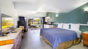 A bedroom with a bed, a TV, a desk, and a view of the outdoors. - Warm Mineral Springs Motel (North Port)
