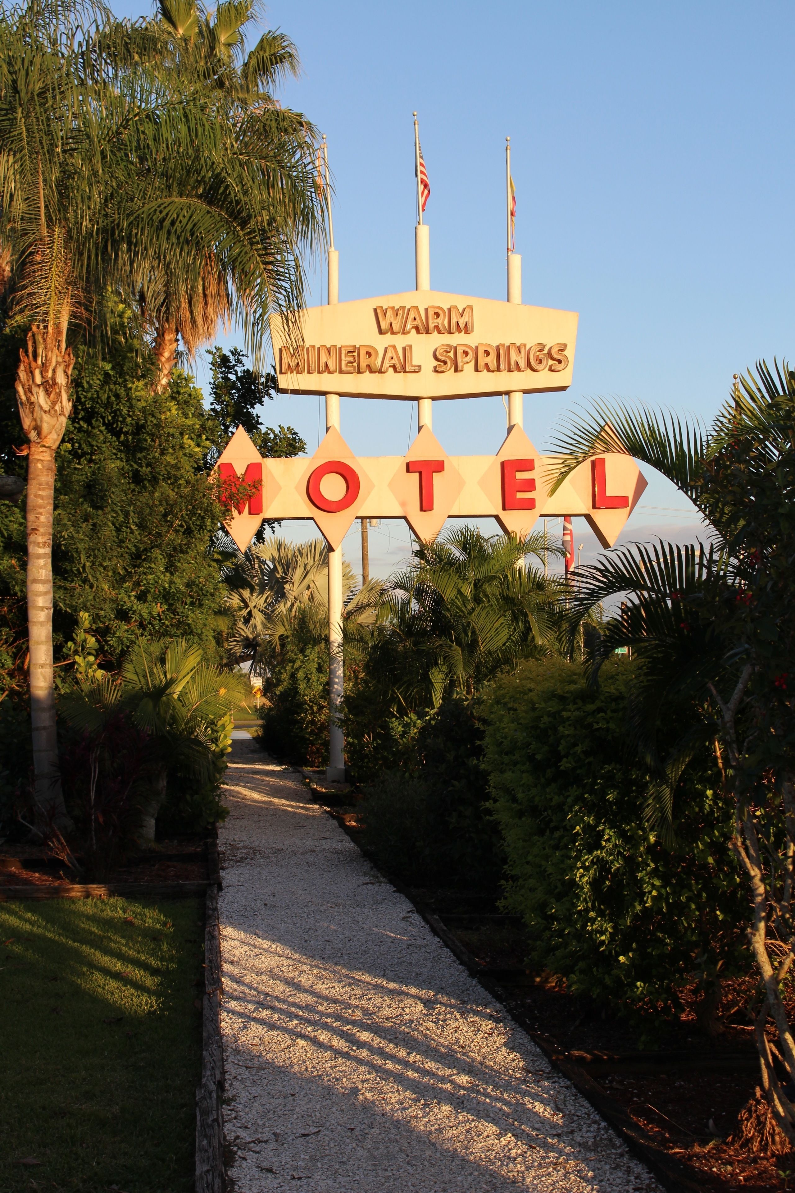 Une enseigne indiquant le « Warm Mineral Springs Motel », avec un chemin menant à l’établissement.