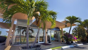 A modern building with large glass doors, palm trees, and potted plants. - Warm Mineral Springs Motel (North Port)