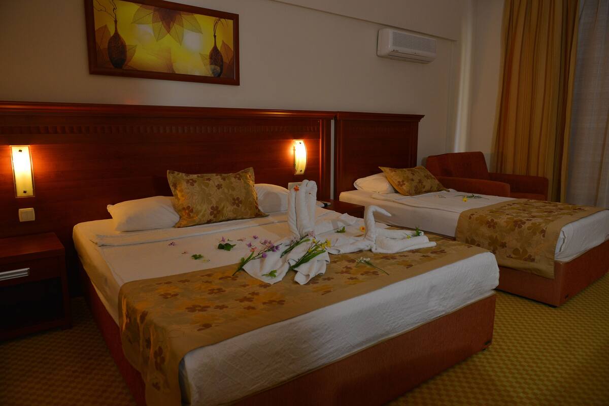 Ein Hotelzimmer mit zwei Betten, einem Nachttisch, einem Sessel und einem Bild an der Wand.