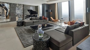 Un salon moderne avec un grand piano, un ensemble de canapés et une vue sur la ville.