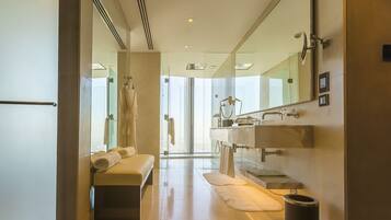 A modern bathroom with a bench, a large mirror, a sink, and a bidet.