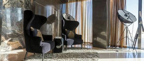 Un interior moderno con dos sillones negros, una alfombra mullida, un espejo grande y una antena parabólica.