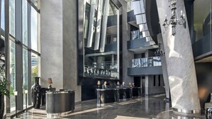 Un hall d’entrée moderne avec un comptoir d’accueil, de grandes fenêtres et une colonne en marbre.