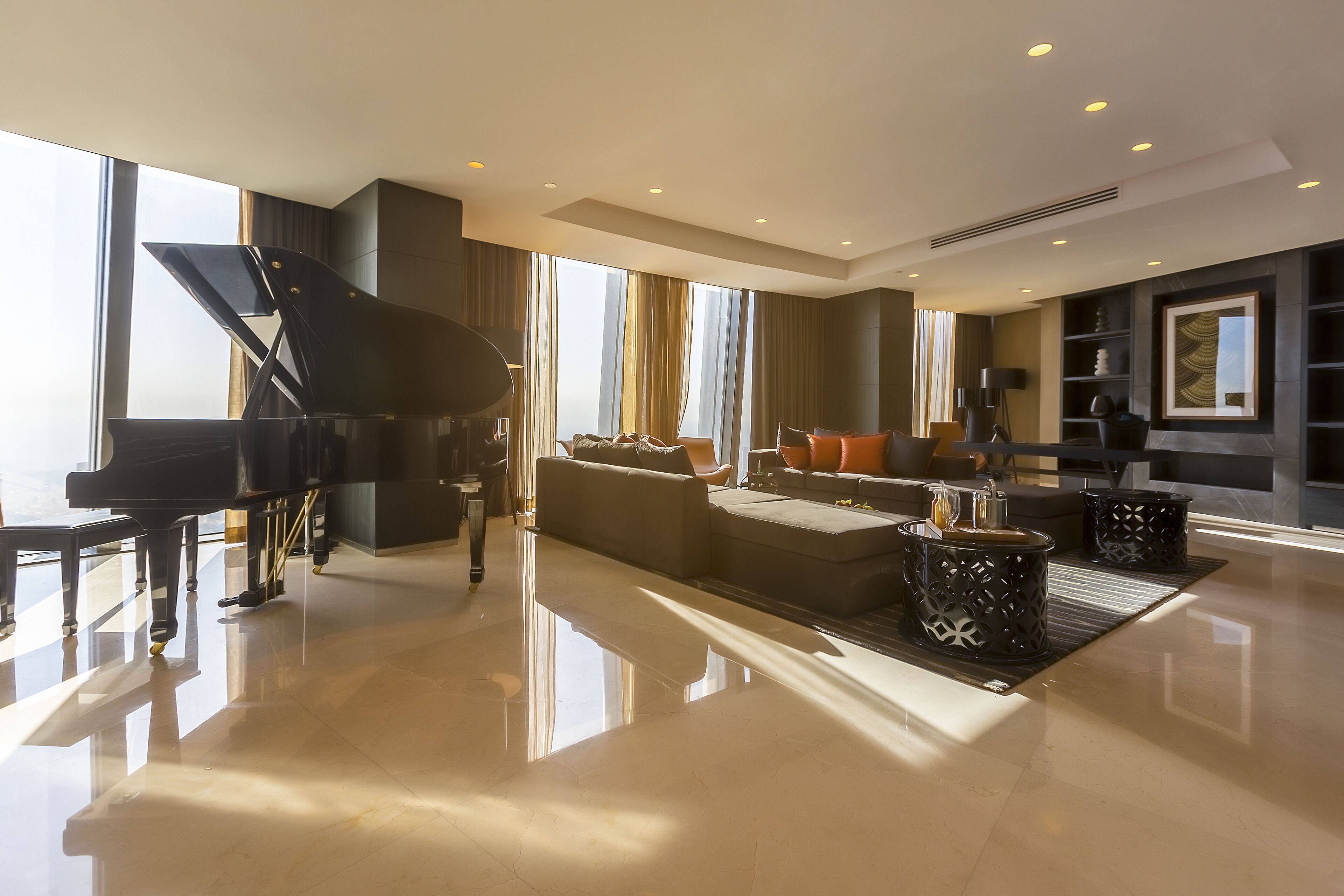 A spacious living room with a grand piano, comfortable seating, and a large window providing natural light.