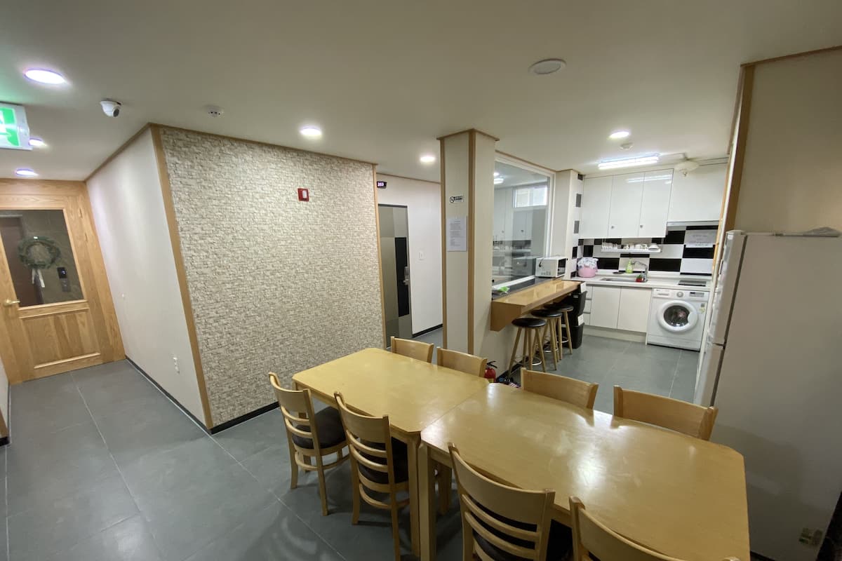 A dining area with a wooden table and chairs, a kitchen with appliances, and a textured wall.