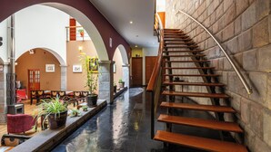 A spacious lobby with a central staircase, multiple seating areas, and potted plants. - Hotel Mamasara (Cusco)