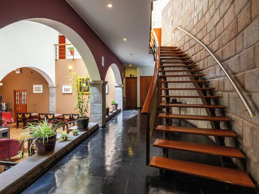 A spacious lobby with a central staircase, multiple seating areas, and potted plants.