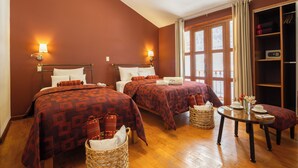 A hotel room with two beds, a wooden floor, a table with a vase and cups, and a wardrobe. - Hotel Mamasara (Cusco)