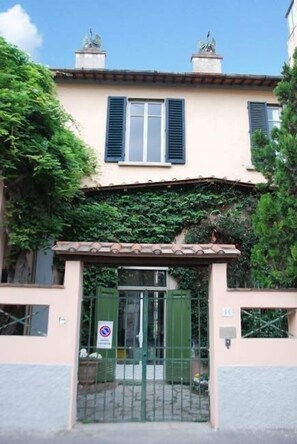 A two-story building with a gated entrance, a balcony, and a small garden area. - B&B Casa Schlatter (Florence)