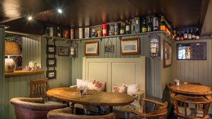 Un rincón de bar acogedor con mobiliario de madera, una variedad de botellas y cuadros en la pared.