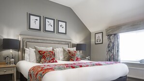 Un dormitorio con una cama grande, una mesita de noche con lámpara y cuadros en la pared.