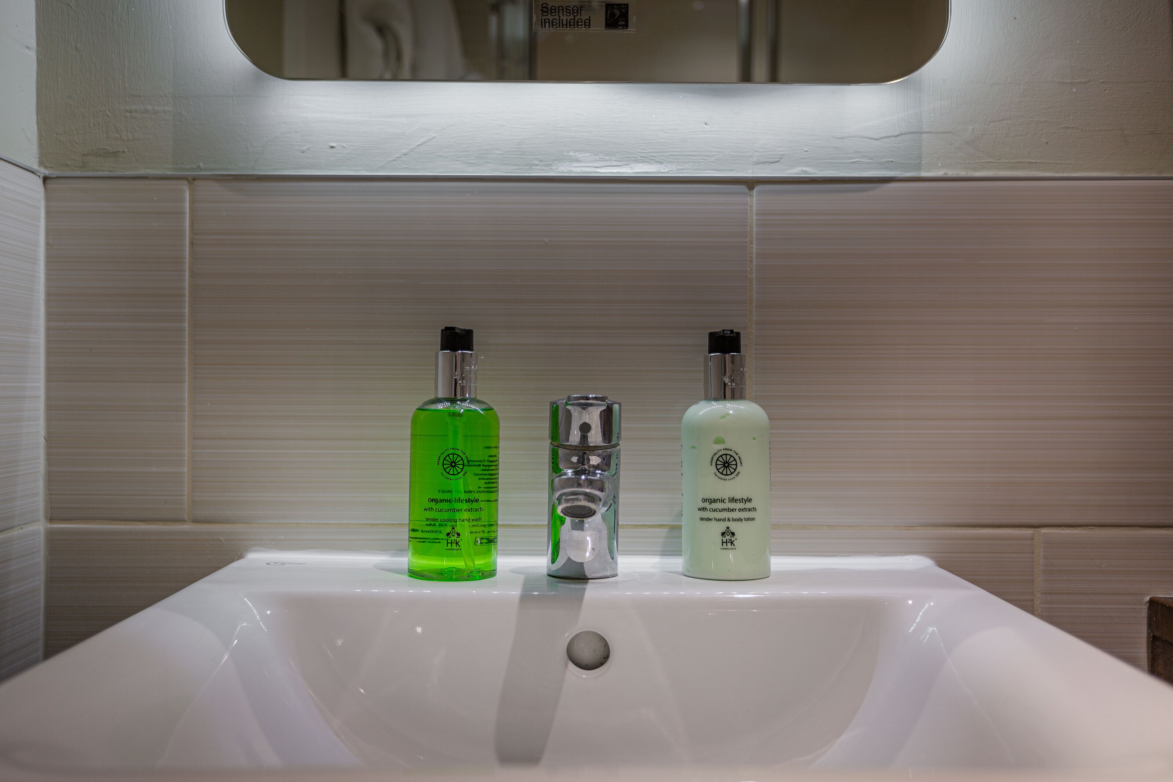 A bathroom sink with three bottles of liquid soap.
