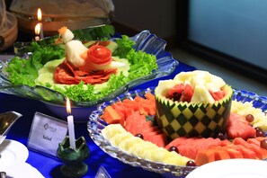 Ein Tisch mit Salat, Obstschale und Kerze.