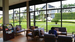 Un hall d’hôtel moderne, doté de grandes fenêtres, de sièges confortables et d’un espace d’accueil.
