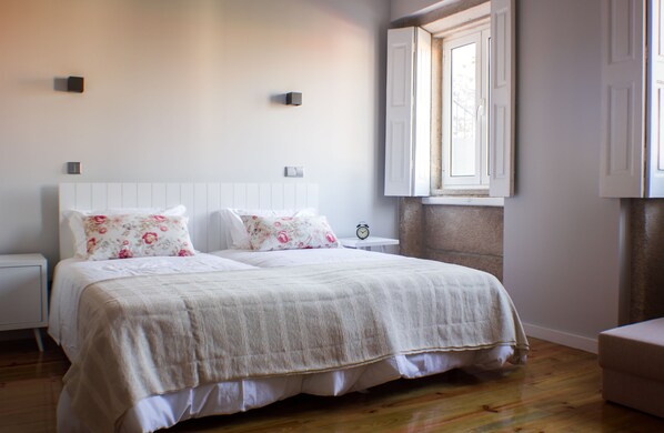 A bedroom with a large bed, two bedside tables, a nightstand, and a window with a view. - Oporto Trendy Apartments (Porto)