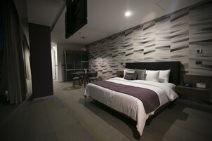 Una habitación de hotel moderna con una cama grande, un escritorio y una zona de estar.