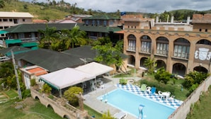 Una piscina con diseño de cuadros, rodeada por un puente de piedra y un edificio con escudo heráldico.