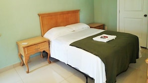 A single bed with a wooden headboard, a bedside table, and a nightstand. - Be Inn Punta Gorda (Punta Gorda)