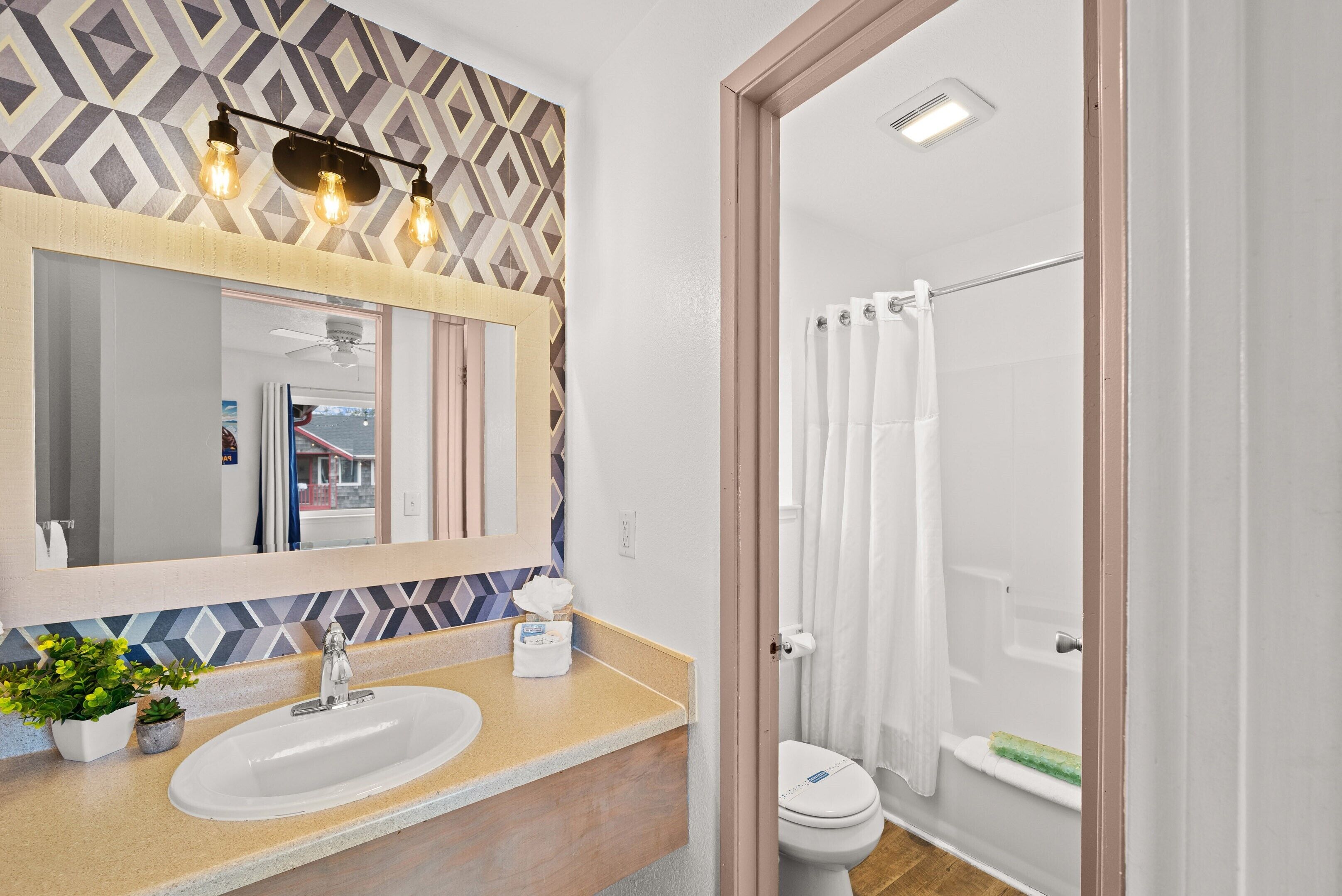 A bathroom with a beige countertop, a white sink, a mirror, and a shower curtain.