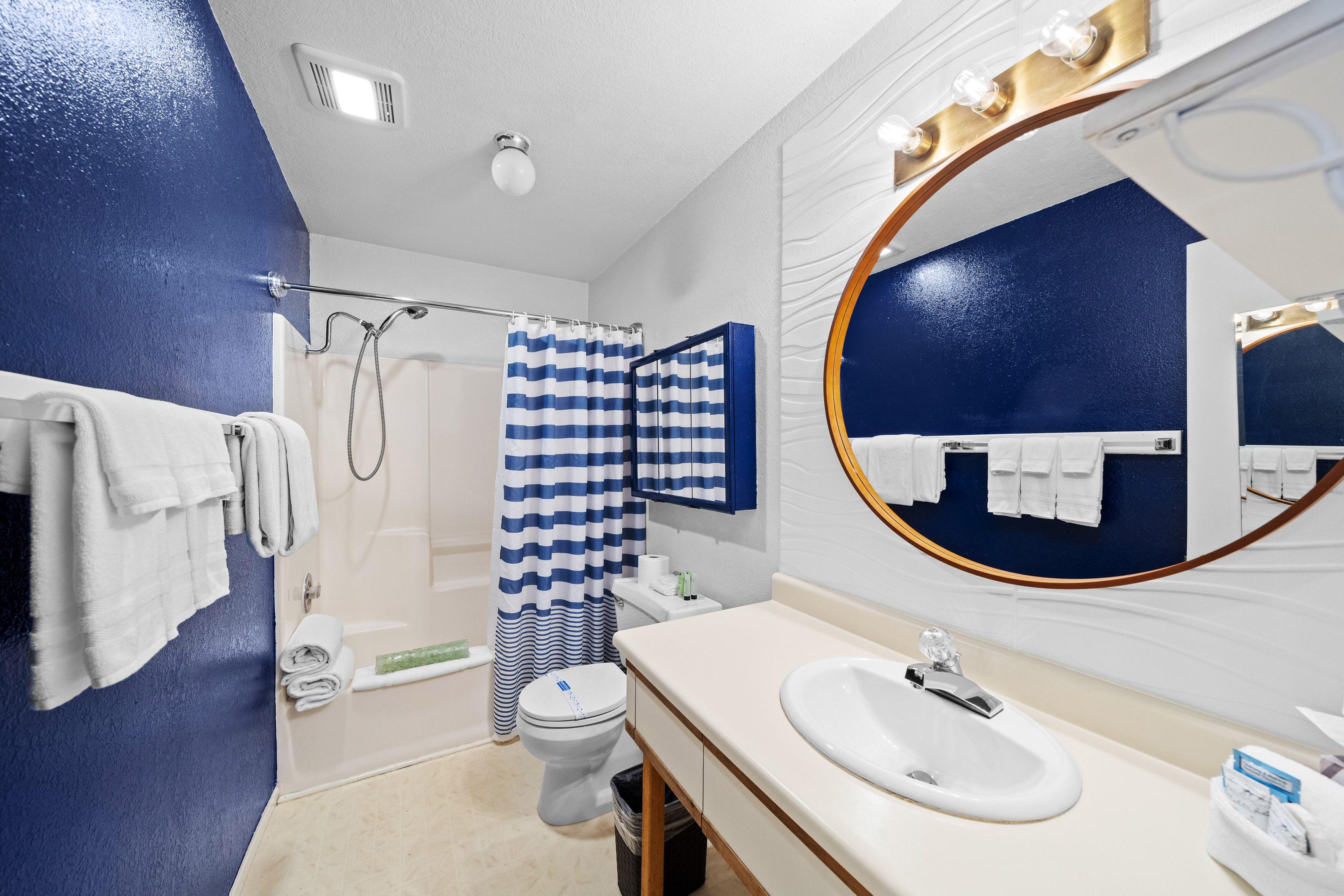 A modern bathroom with a large mirror, white sink, and shower area.