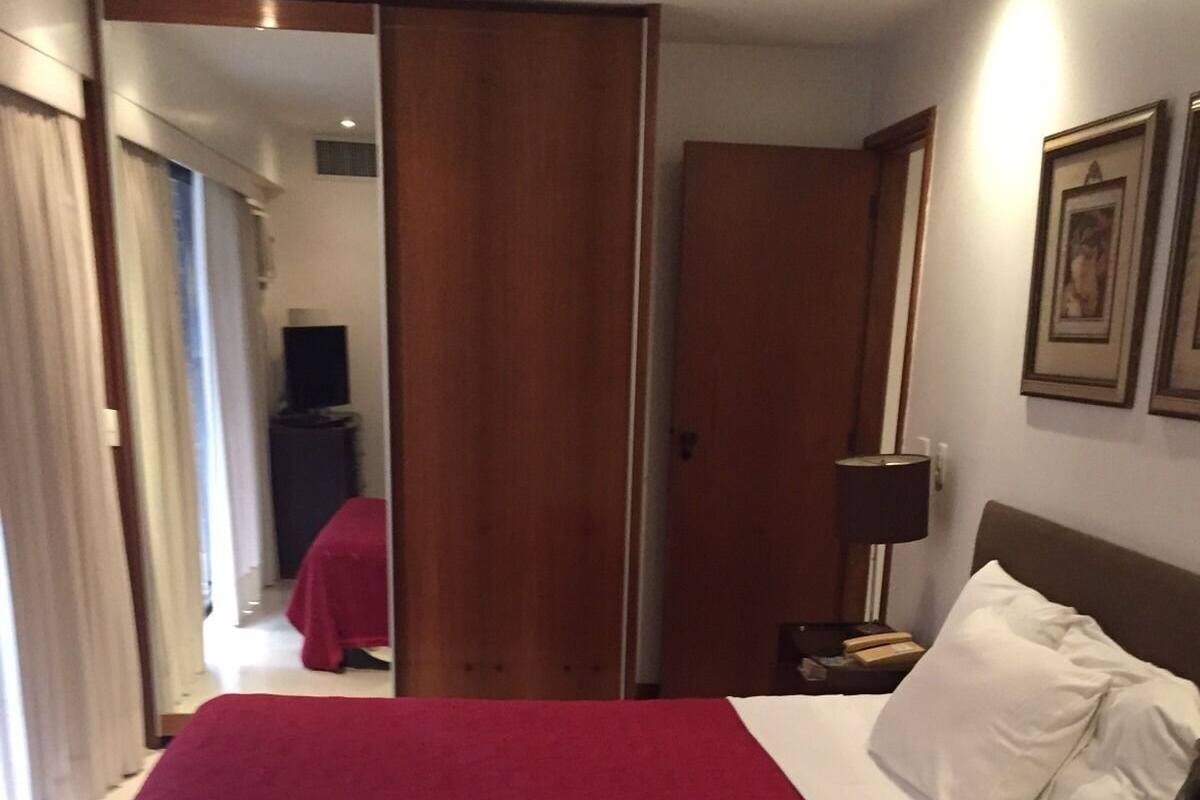 Une chambre d’hôtel avec un lit, une table de chevet, une lampe et un miroir.