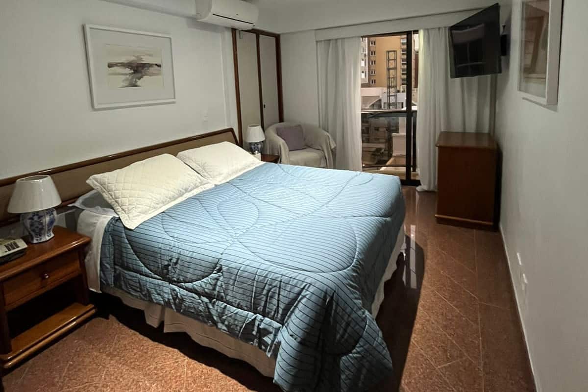 Une chambre d’hôtel équipée d’un lit, d’une table de chevet, d’un appareil de climatisation, d’un téléviseur et offrant une vue sur l’extérieur.