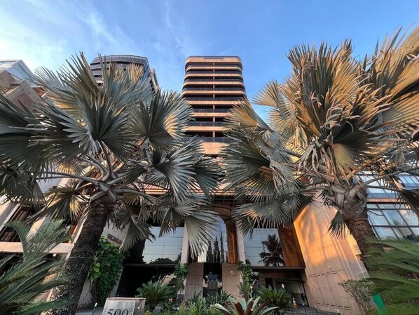 A modern building with a central atrium surrounded by palm trees.