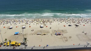 Una playa concurrida, llena de sombrillas y gente.