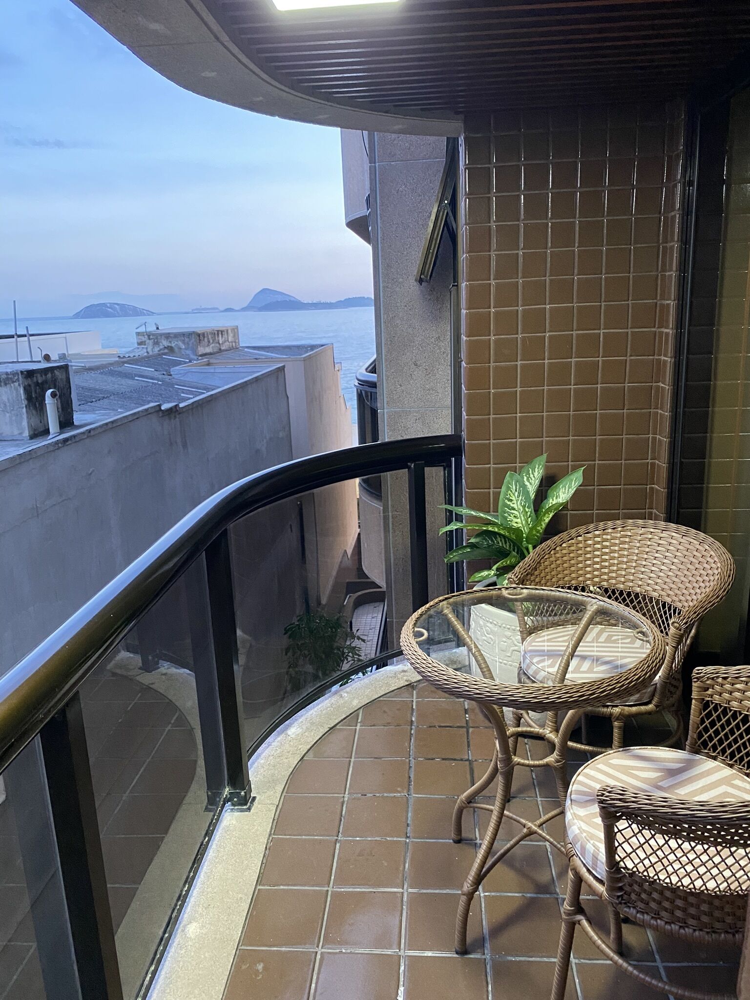 A balcony with a view of the sea, wicker furniture, and tiled walls.