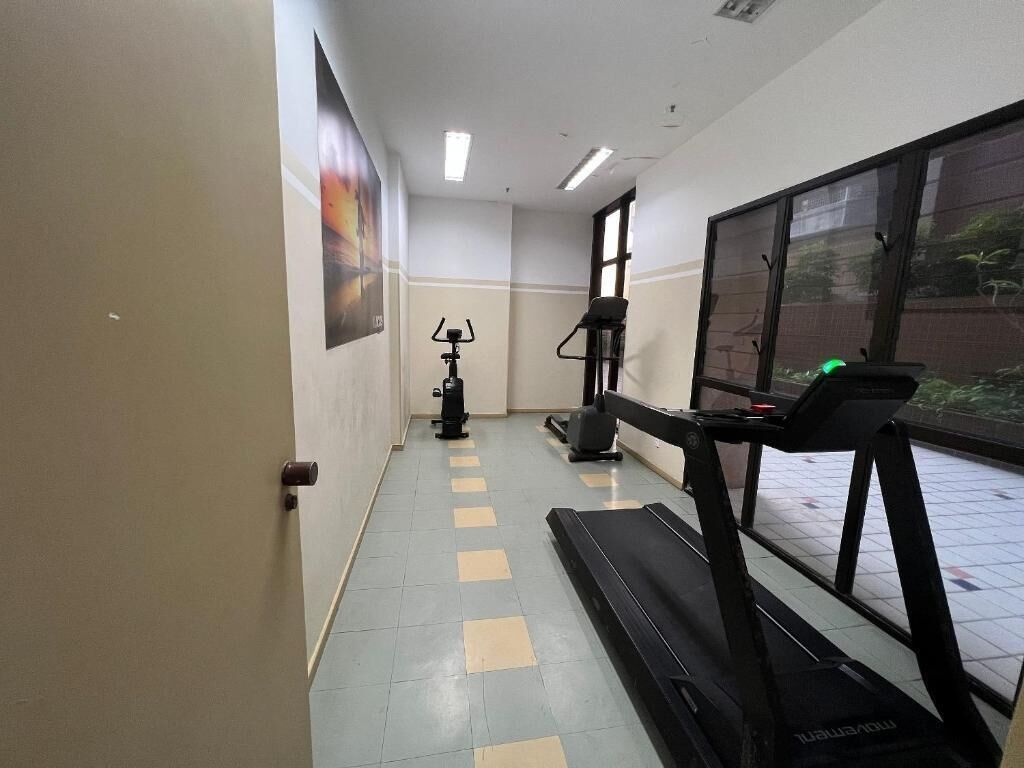 A hallway with a treadmill, stationary bike, and a wall-mounted exercise machine.