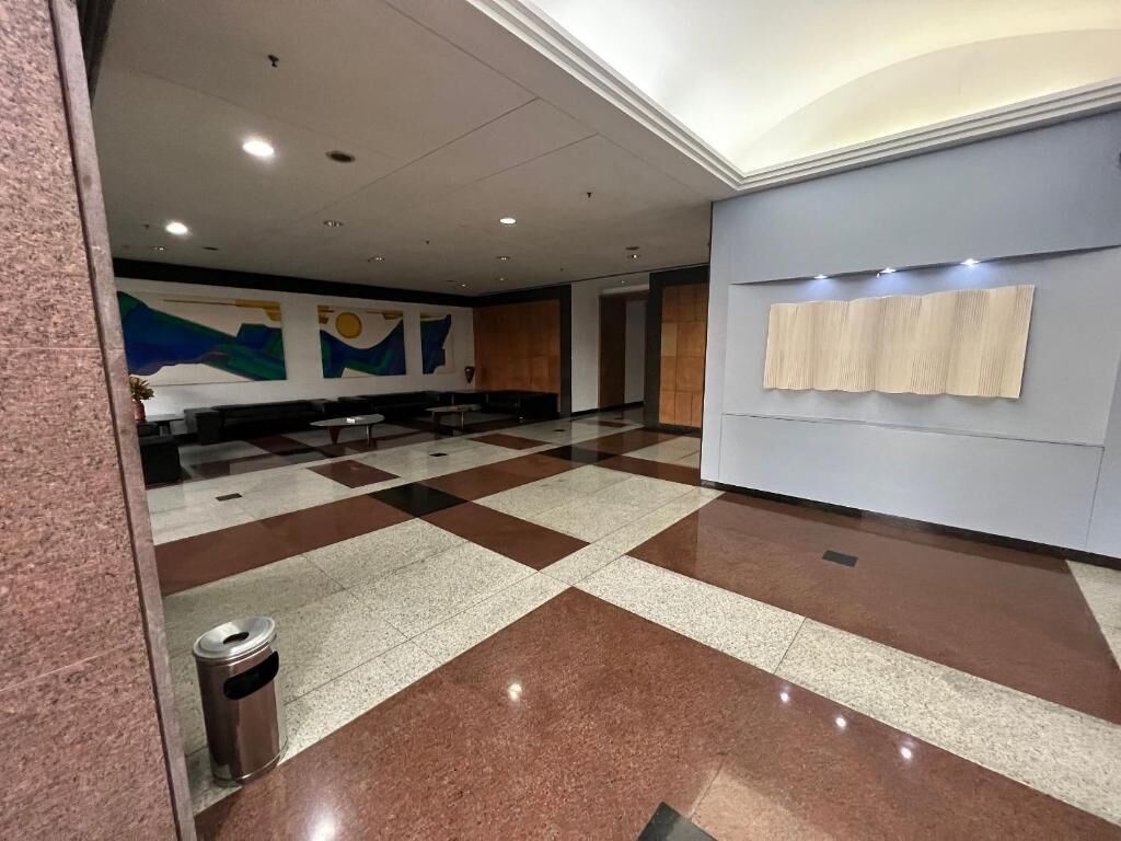 Un hall d’hôtel avec un sol à carreaux, une poubelle et un mur sur lequel est fixé un porte-serviettes.