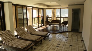 Una habitación iluminada por el sol con sillones a rayas, una mesa de madera y vistas amplias a través de grandes ventanales.