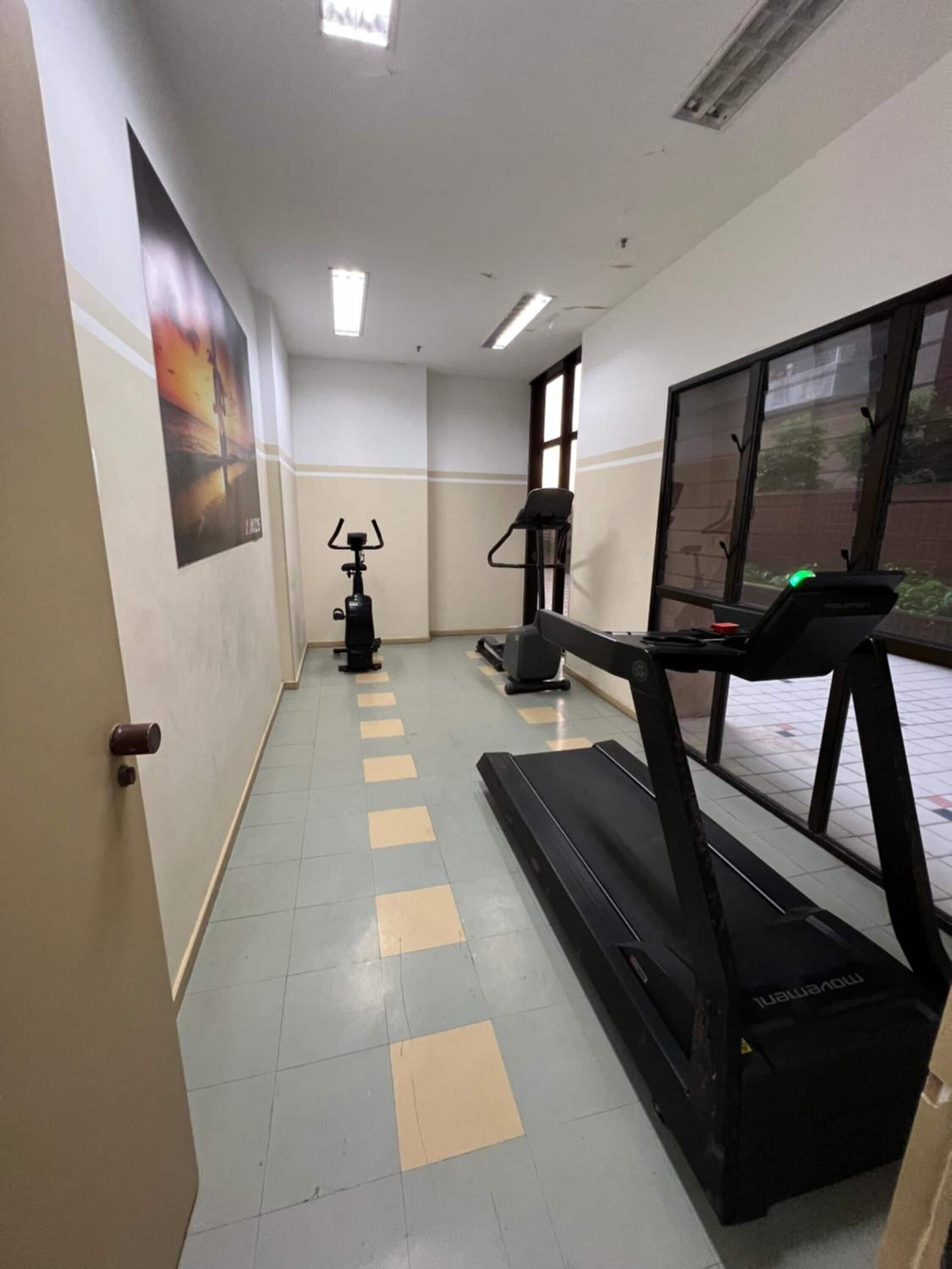 A fitness room with treadmills, a stationary bike, and a wall-mounted exercise machine.