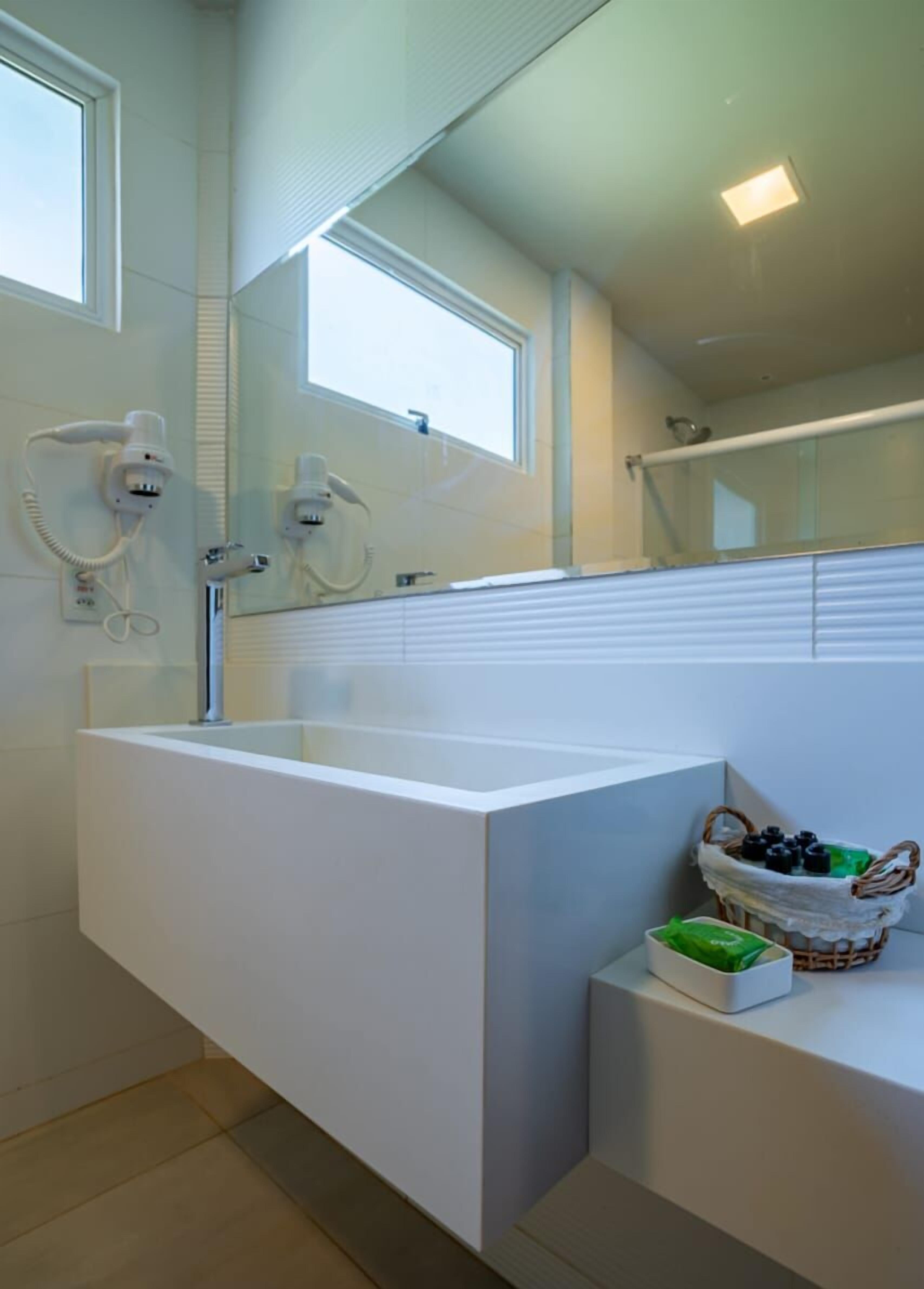 Un baño moderno con una bañera blanca grande, un espejo sobre el lavamanos y una ventana que proporciona luz natural.