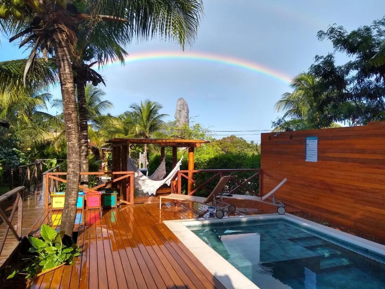 A wooden deck with a pool, a hammock, and a wooden structure.