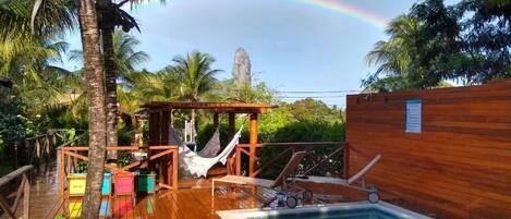 A wooden deck with a pool, a hammock, and a wooden structure.